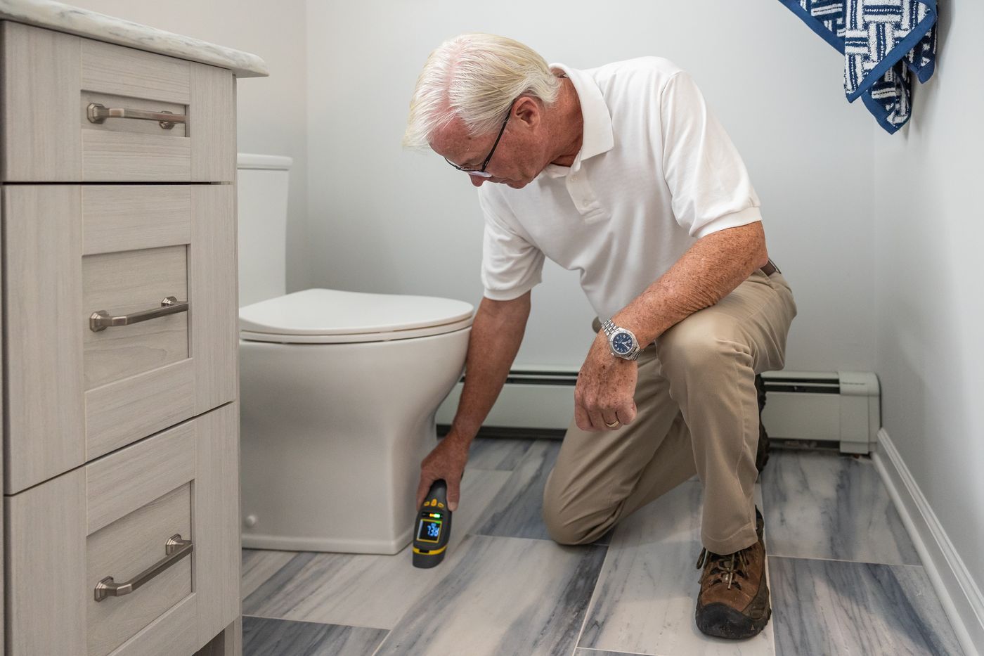 Technician checking a bathroom for plumbing problems during a maintenance visit